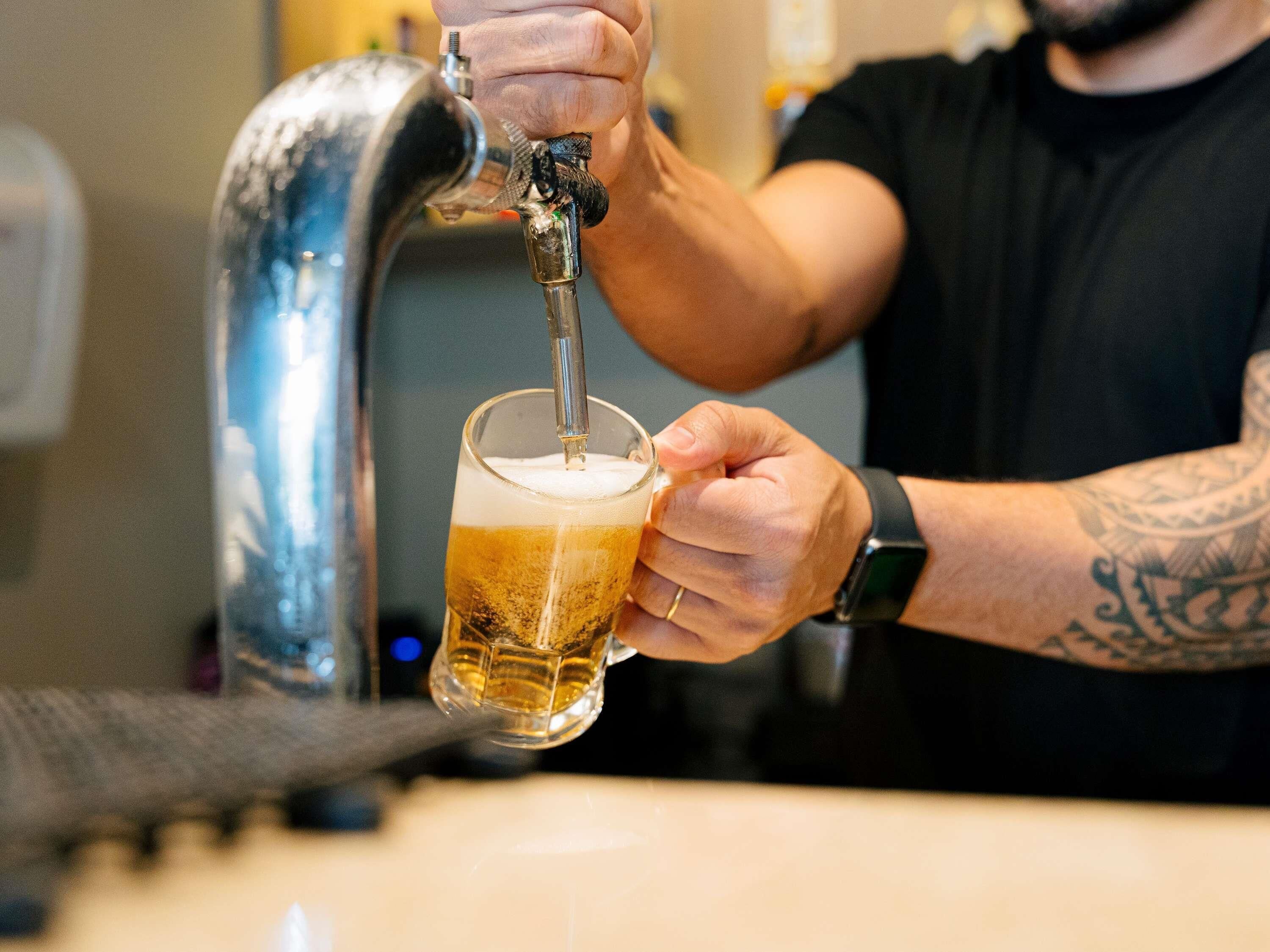 A person pouring beer from a tap into a glass.