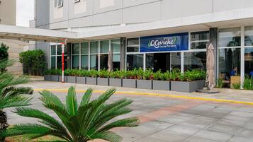 A modern building with a sign reading 'Cocina Peruana' and a covered outdoor area with planters and a palm tree.
