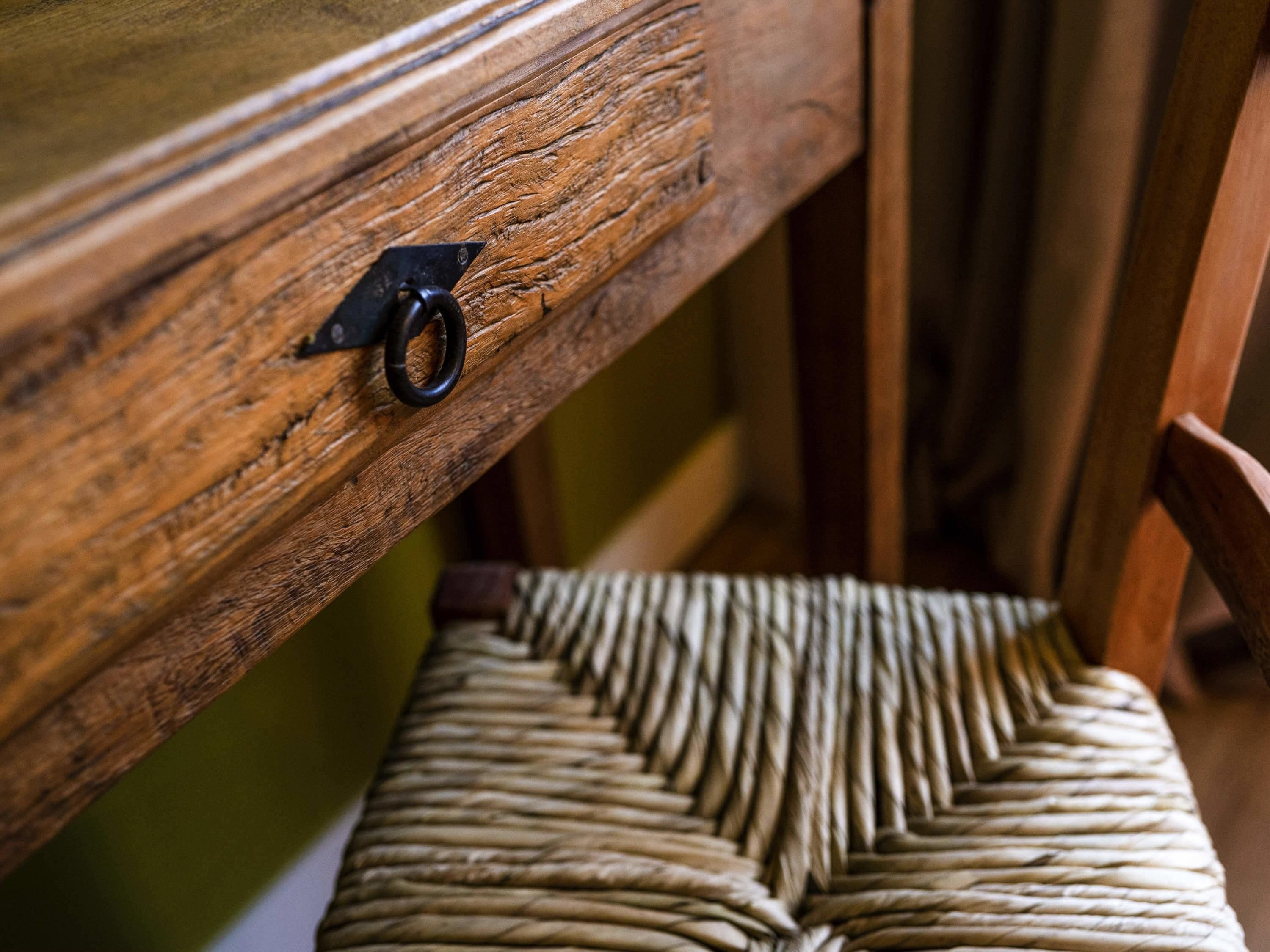A wooden chair with a woven seat and backrest, and a metal latch on the side.