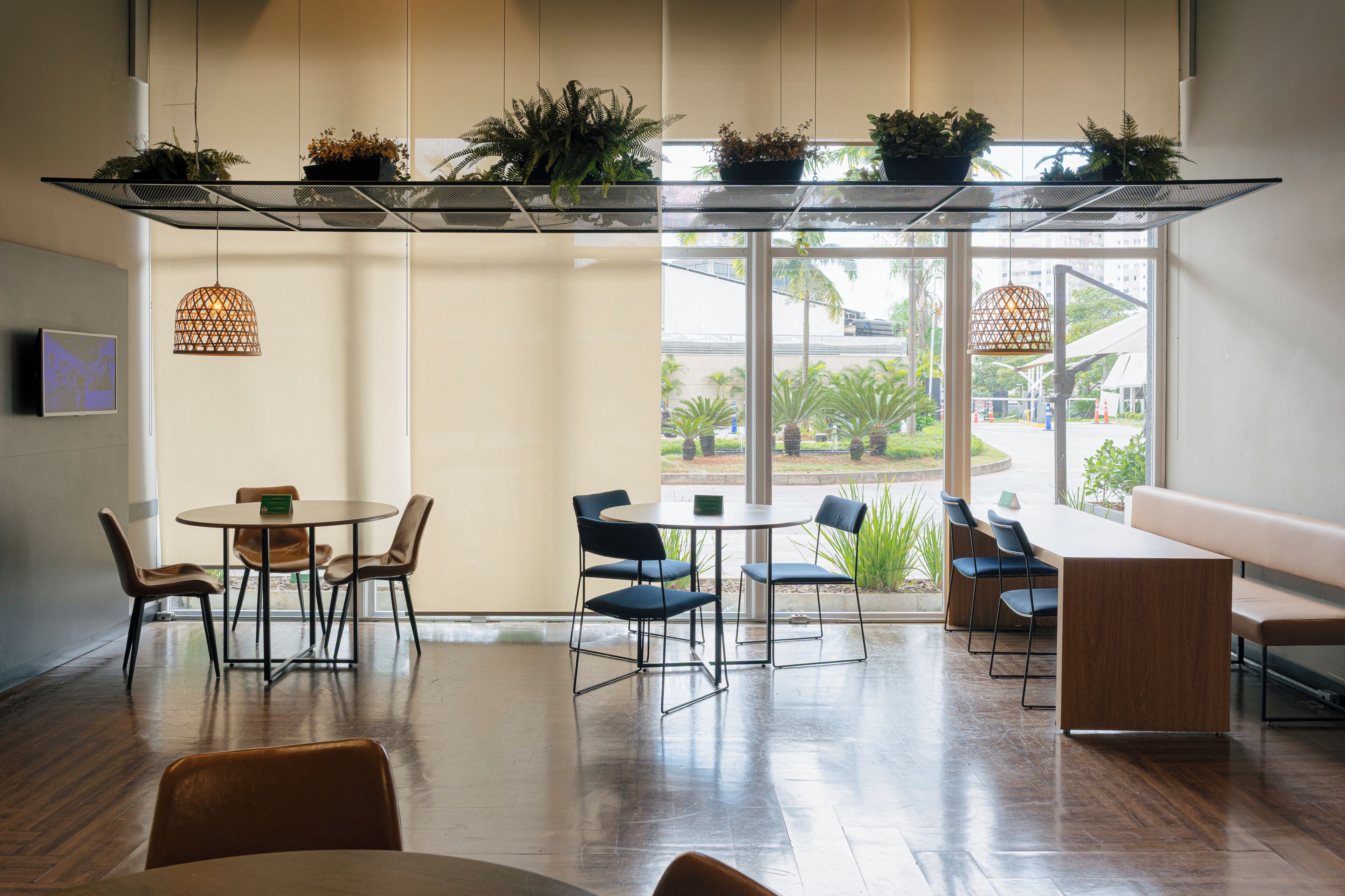 A modern interior with a glass partition, wooden flooring, and multiple seating areas.