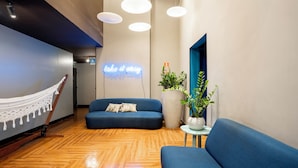 Un intérieur moderne avec un hamac, un canapé bleu et des plantes en pot.