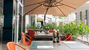 Un espace extérieur aménagé pour les repas, avec des tables, des chaises et des parasols.