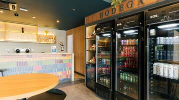 A bar area with a wooden counter, shelves with bottles, and two refrigerators stocked with beverages.