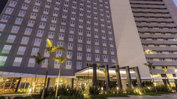 Un hôtel de grande hauteur, doté d’une façade moderne, de nombreux balcons et d’un hall d’entrée bien éclairé.