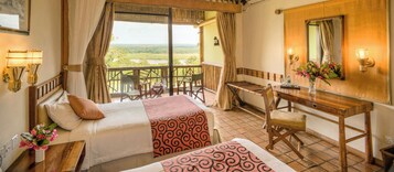 Una habitación de hotel con cama, escritorio, silla, una mesita y vistas al exterior.