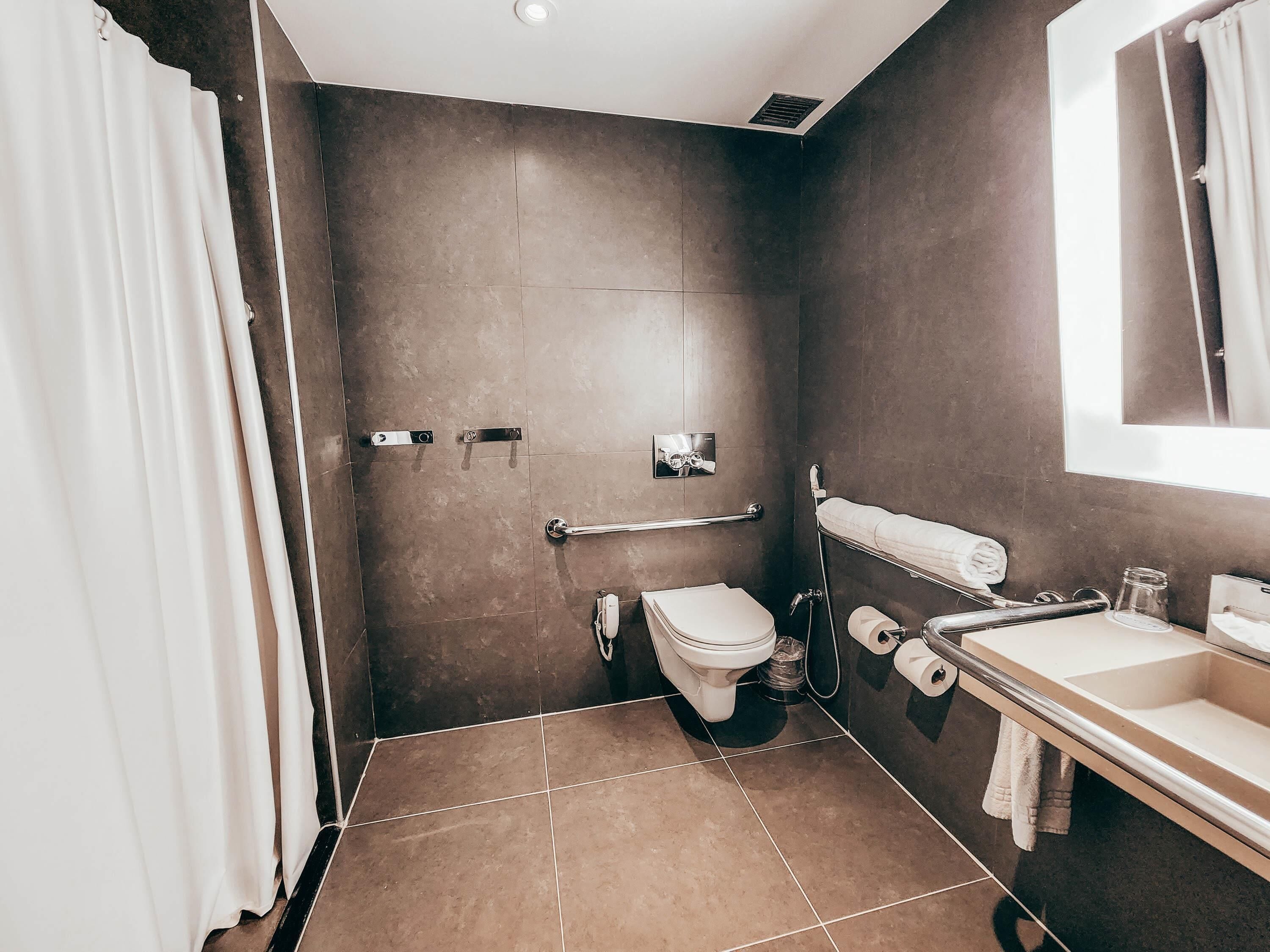A bathroom with a toilet, bidet, towel rack, and a sink.