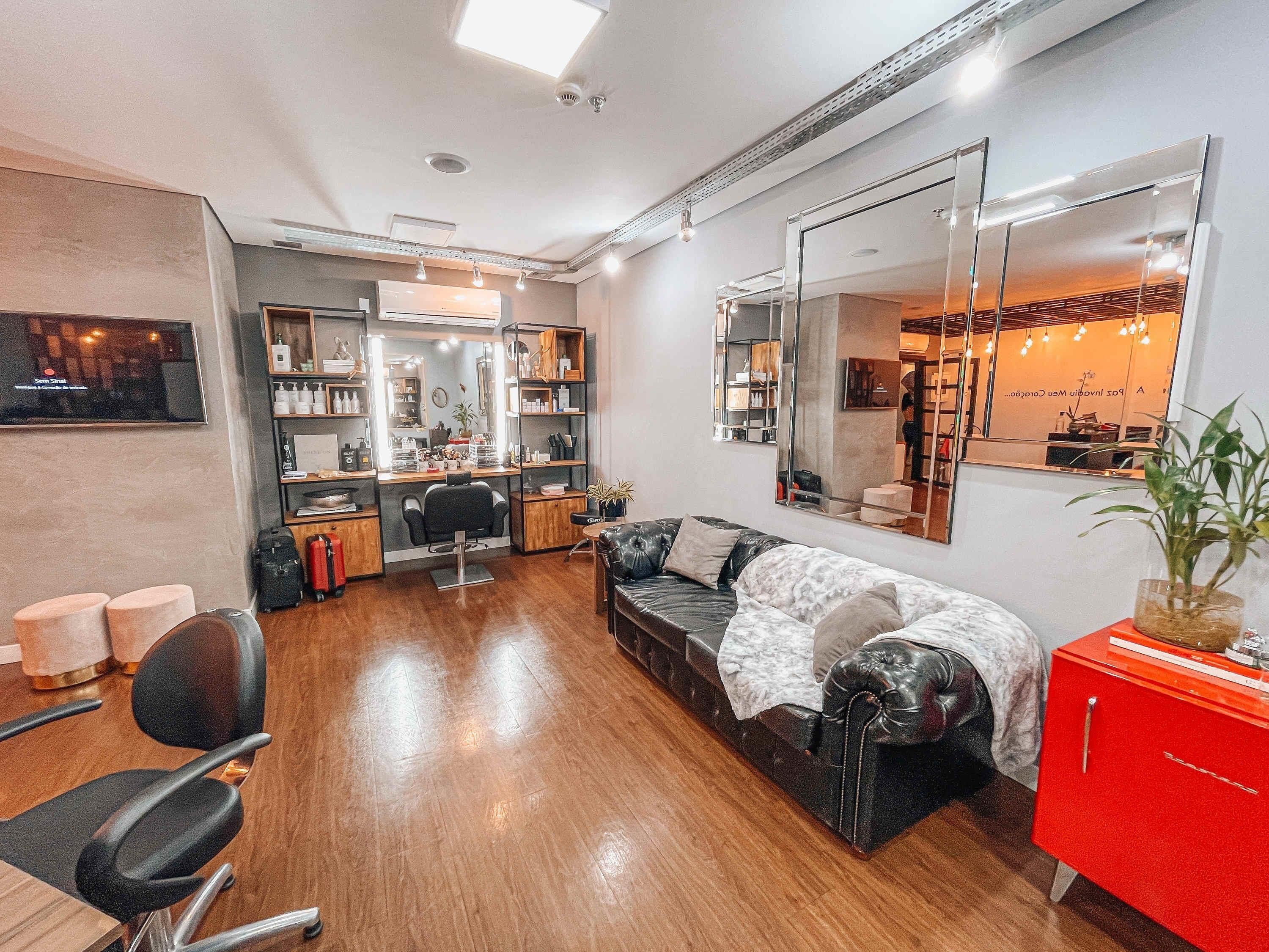A salon with a mirror, chairs, a sofa, and a red cabinet.