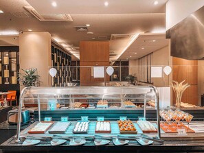 A buffet area with various food items, a seating area with chairs, and a decorative plant. - Novotel RJ Praia de Botafogo Hotel (Rio de Janeiro)