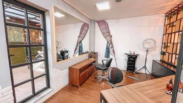 Experience a salon with a clean, organized layout, featuring a large window, reception desk, and comfortable seating.