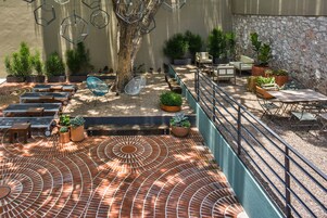 A patio area with outdoor seating, potted plants, and a decorative tiled floor.