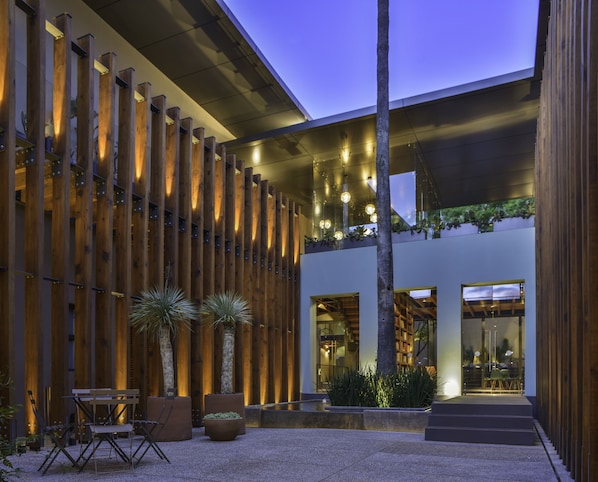 A modern building with a wooden facade, outdoor seating, and a staircase leading to an entrance. - Hotel Criol (Querétaro)