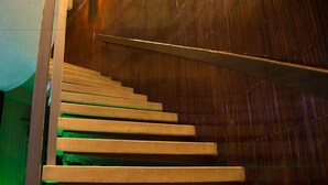 A wooden staircase with a handrail, leading upwards.