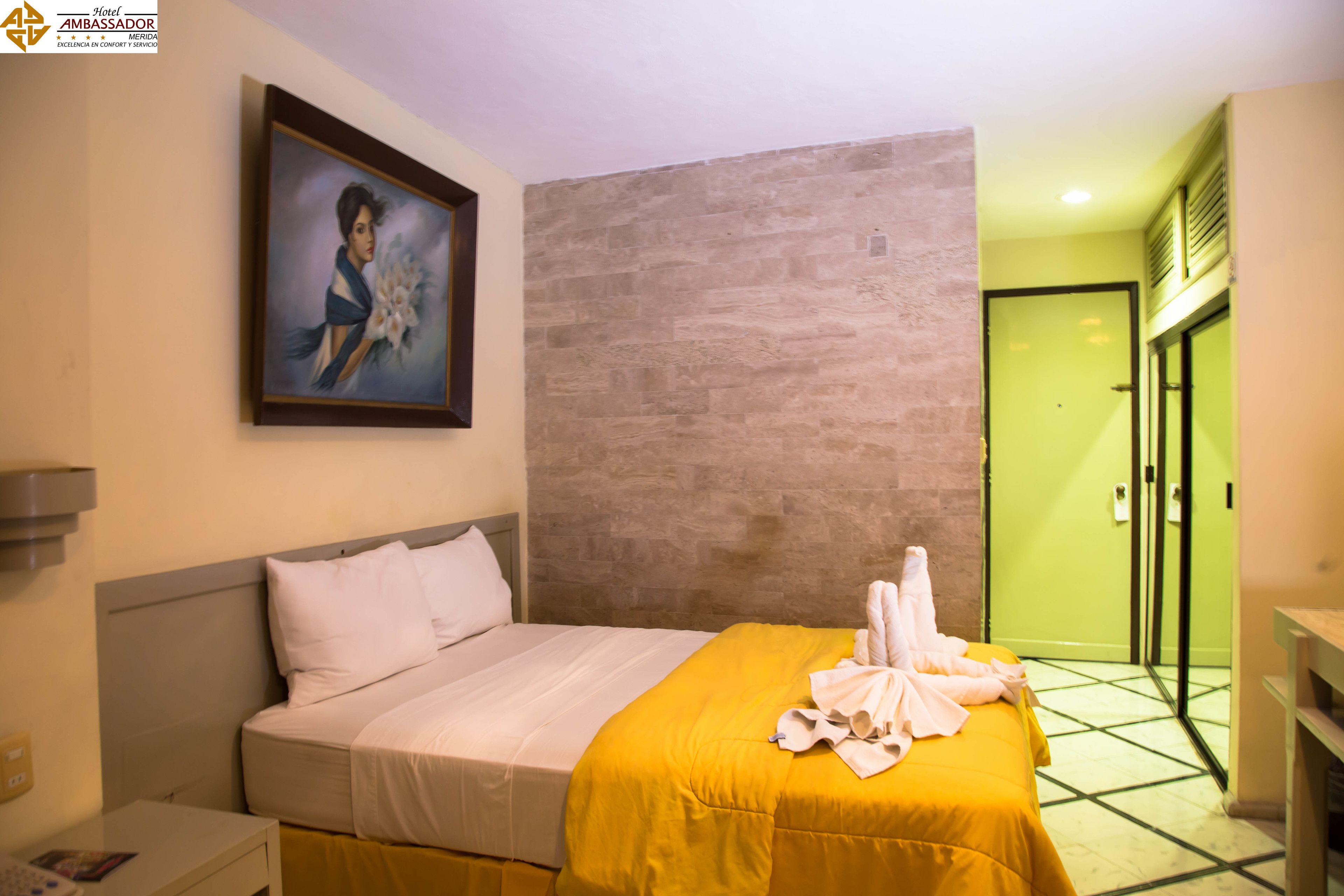 A hotel room with a bed, a painting on the wall, and a green door.