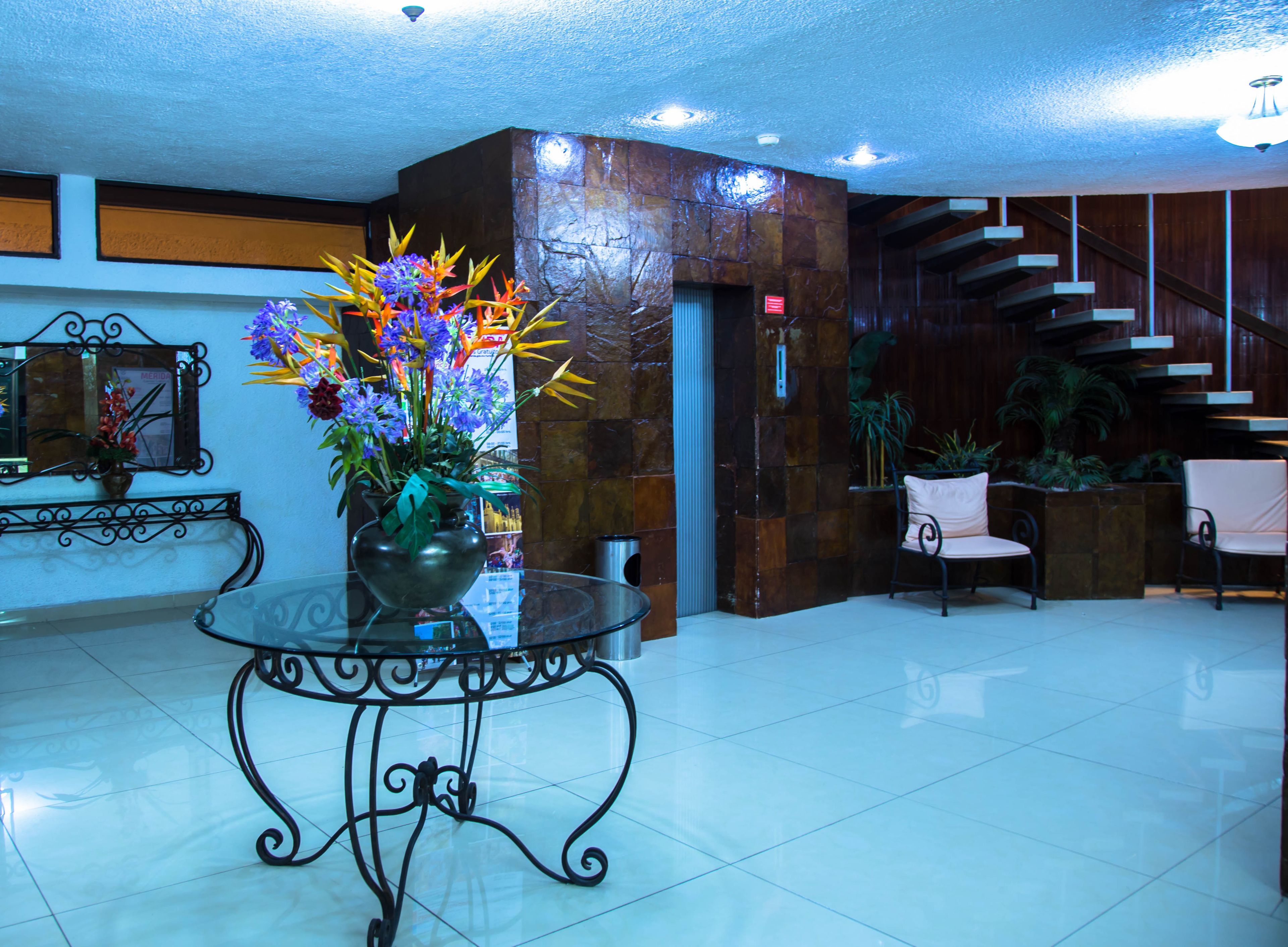 A lobby with a glass table, a flower arrangement, a staircase, and a reception desk.