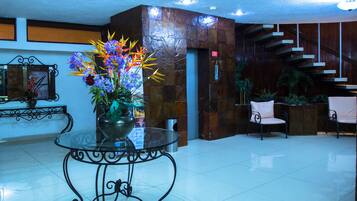 A lobby with a glass table, a flower arrangement, a staircase, and a reception desk.