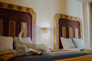 A hotel room with two beds, each with a headboard and pillows.