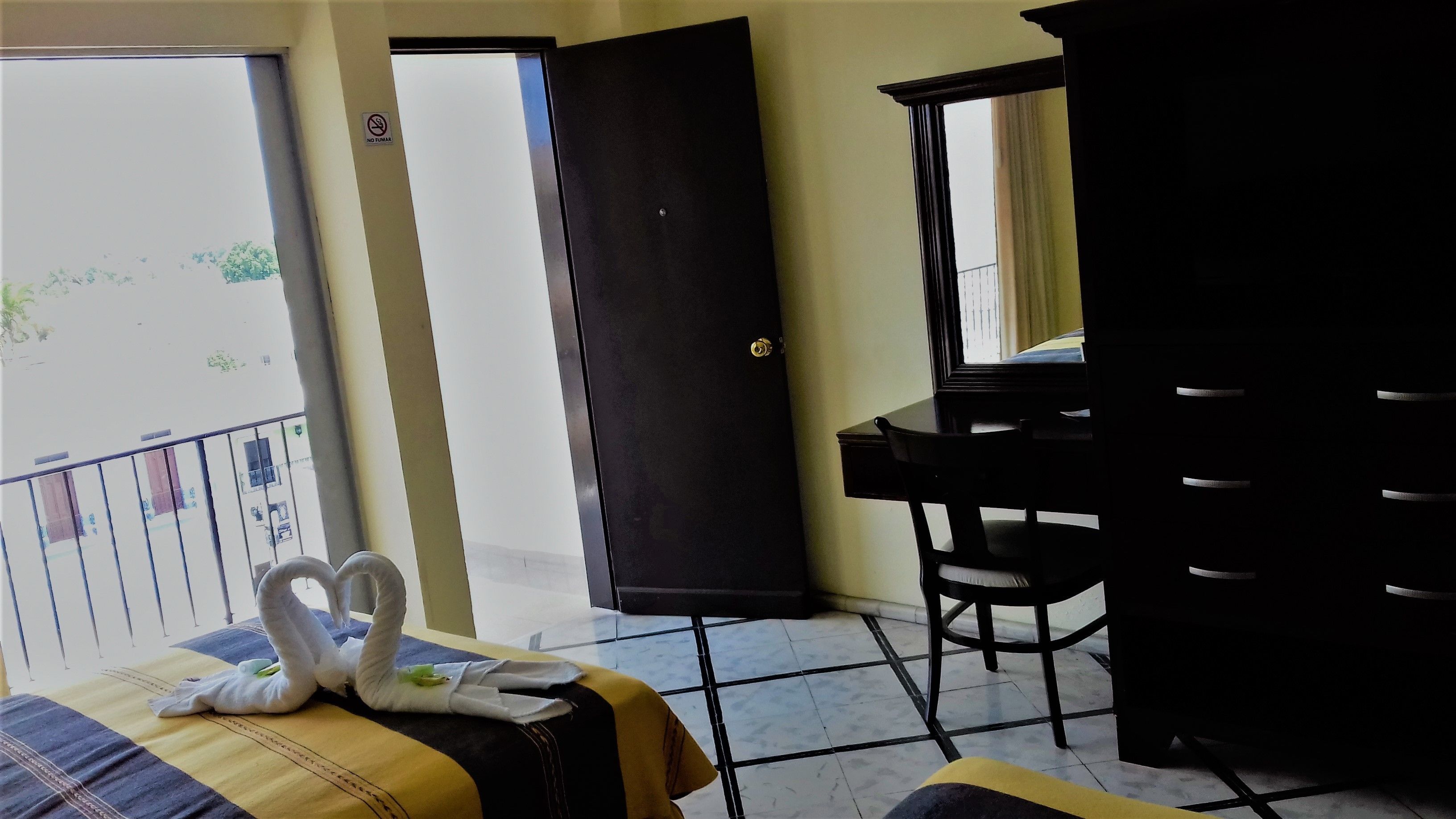 A hotel room with a bed, a desk, a chair, and a wardrobe.