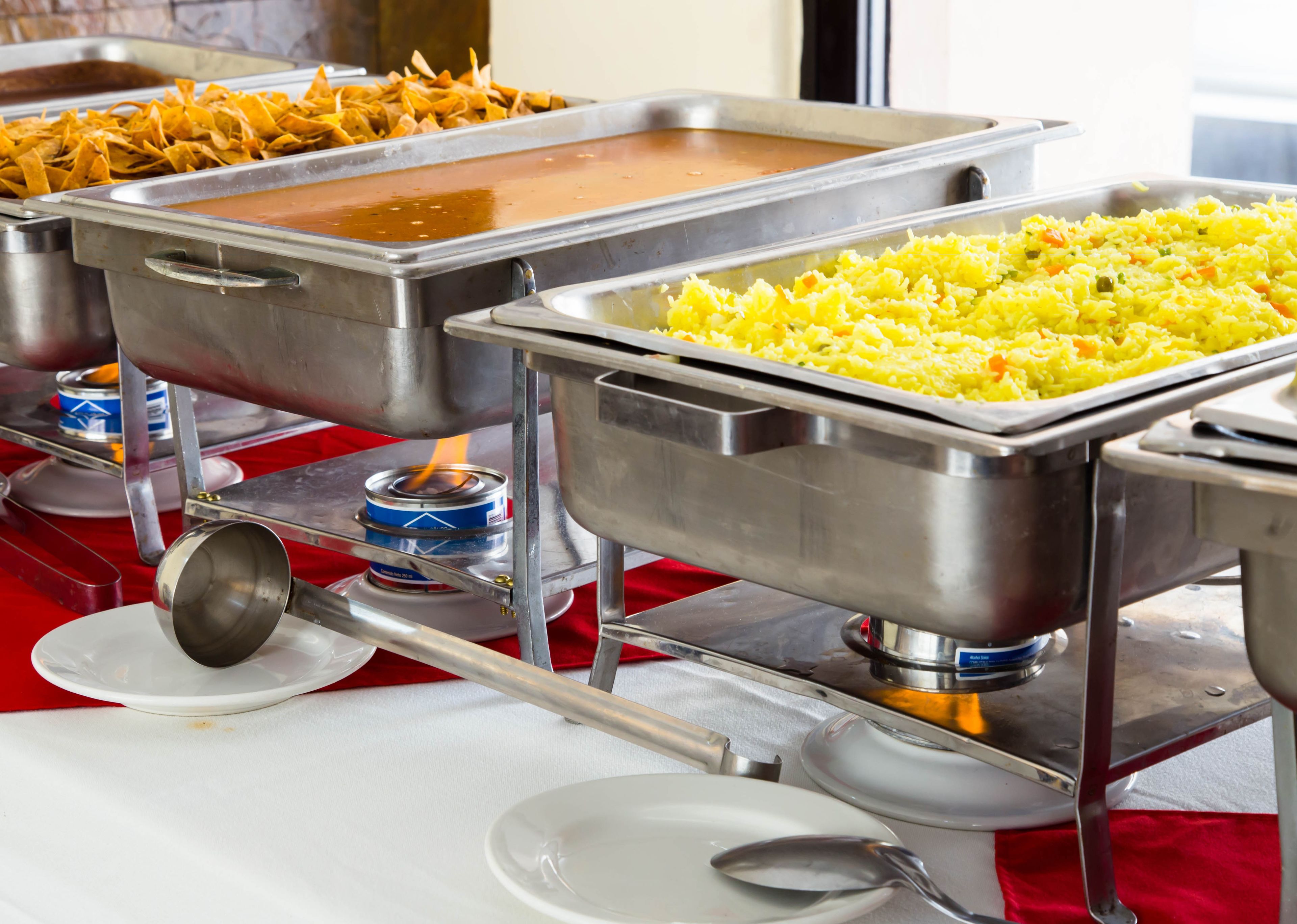 A buffet with various food options including nachos, rice, and soup.