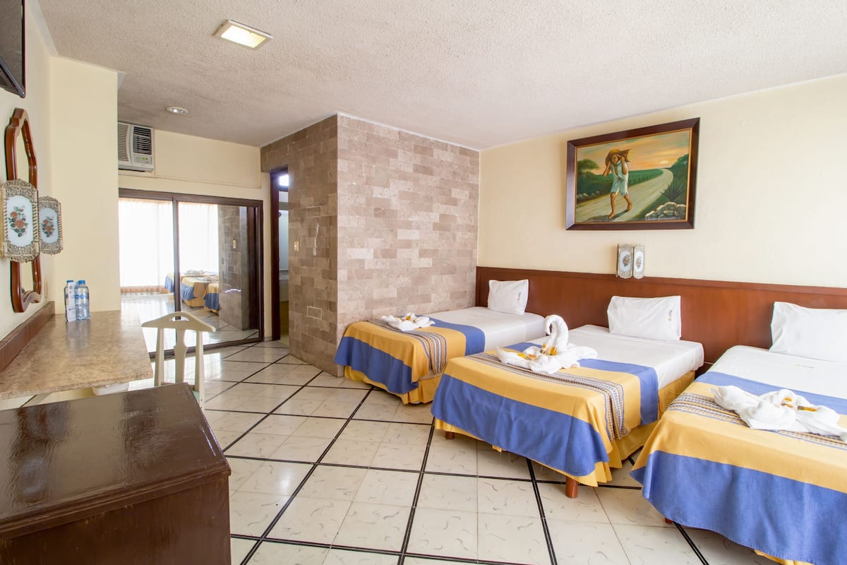 A hotel room with two beds, a wooden desk, a chair, and a painting on the wall.