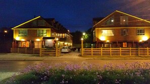 A two-story building with a signboard, a wooden fence, and parked cars. - Hostal Vista al Mar (Ancud)
