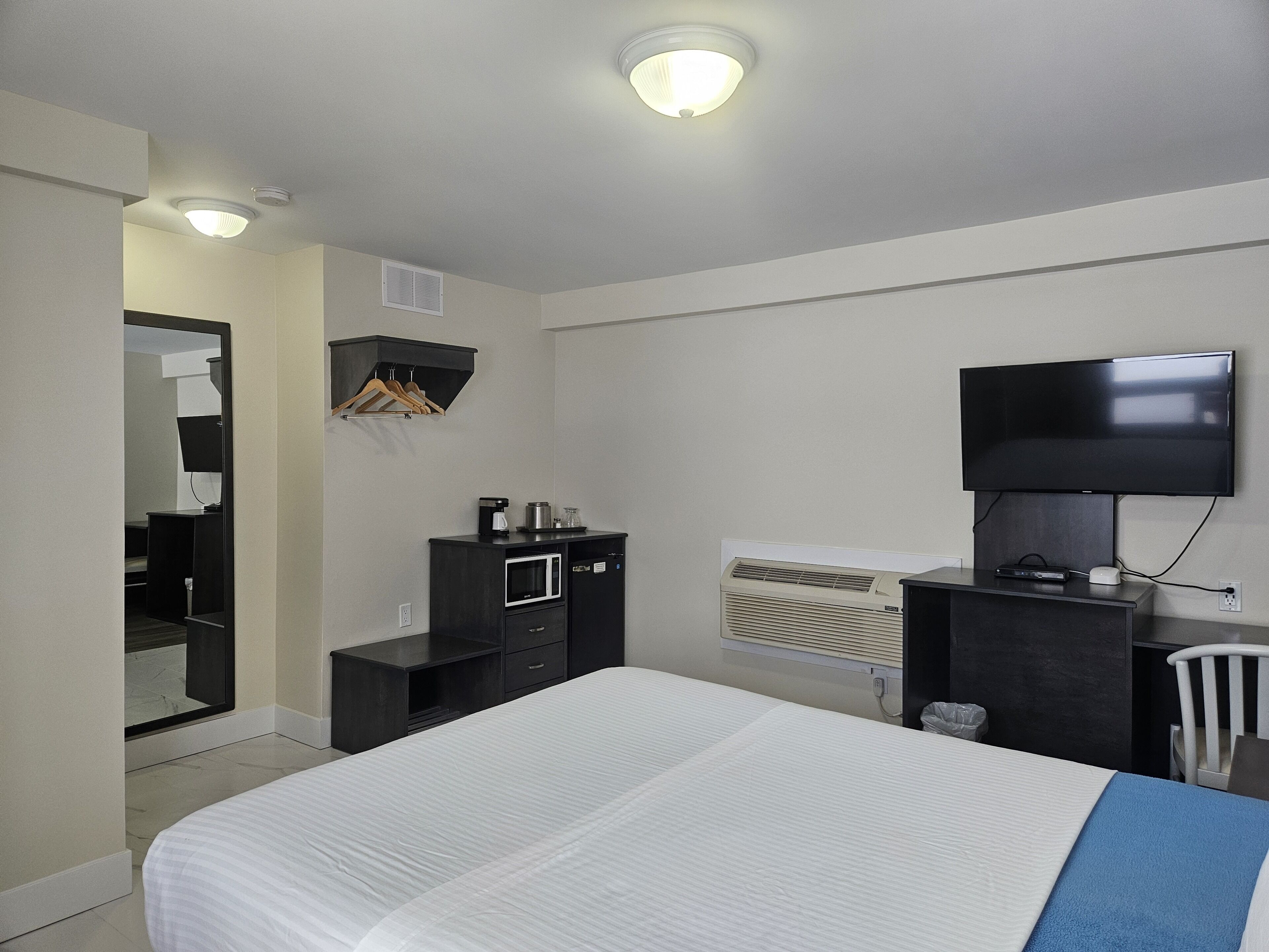Hotelkamer met een bed, een aan de muur bevestigde televisie, een bureau met een computer, een magnetron en een verwarming.