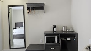 A modern hotel room with a bed, a black minibar, a microwave, and a small seating area. - Leelas Villa Inn Flesherton (Grey Highlands)