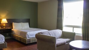 A hotel room with a bed, a chair, a small table, and a lamp. - Leelas Villa Inn Flesherton (Grey Highlands)