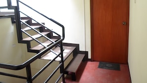 Una escalera con barandillas metálicas que conduce a una puerta de madera con la leyenda 'Hab. 07'.