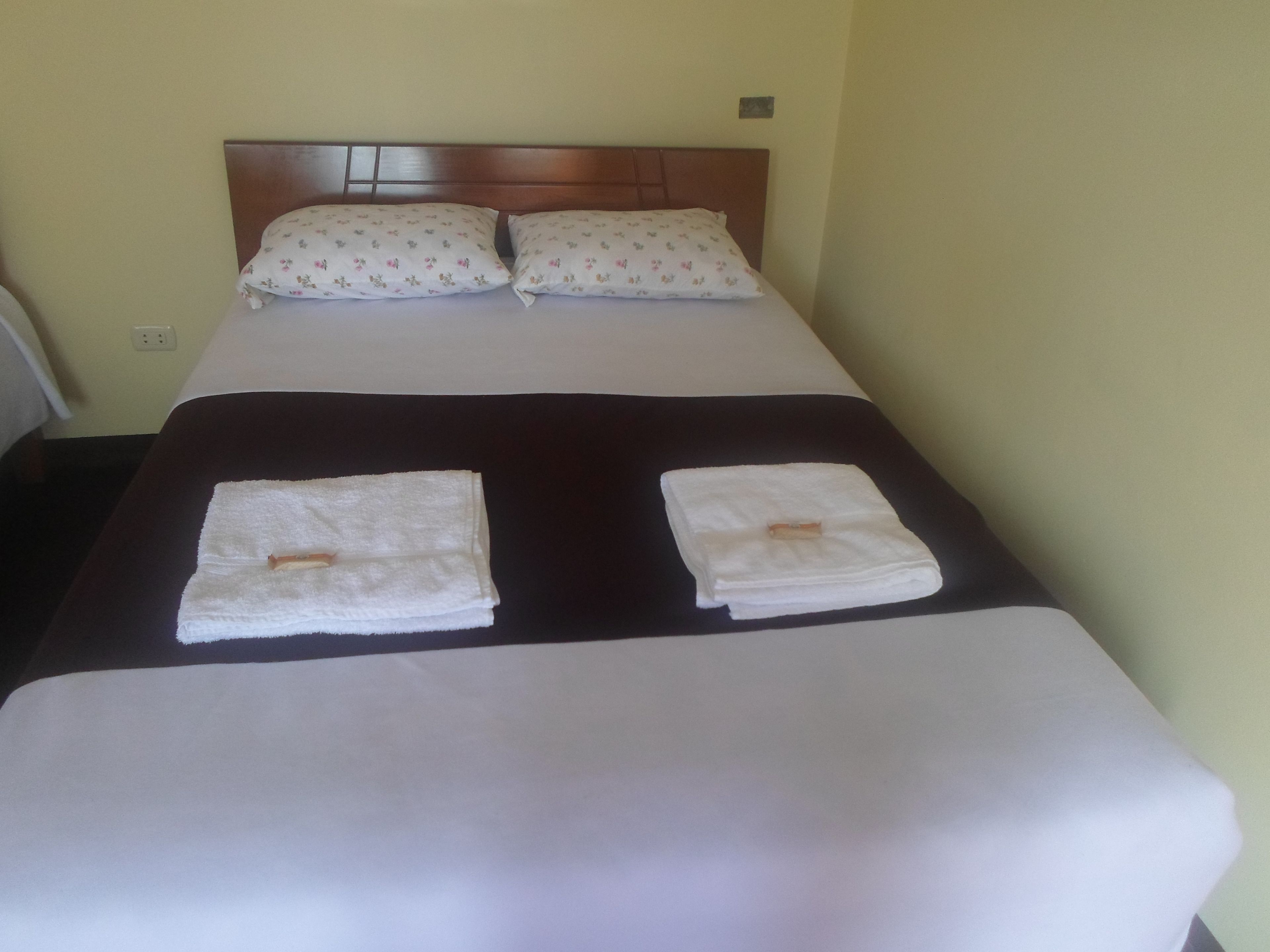 A neatly made bed with two pillows and two folded towels on the bed.
