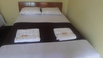 A neatly made bed with two pillows and two folded towels on the bed.