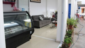 Een modern interieur met een auto op de voorgrond, een grijze bank en een wandplank met flessen.