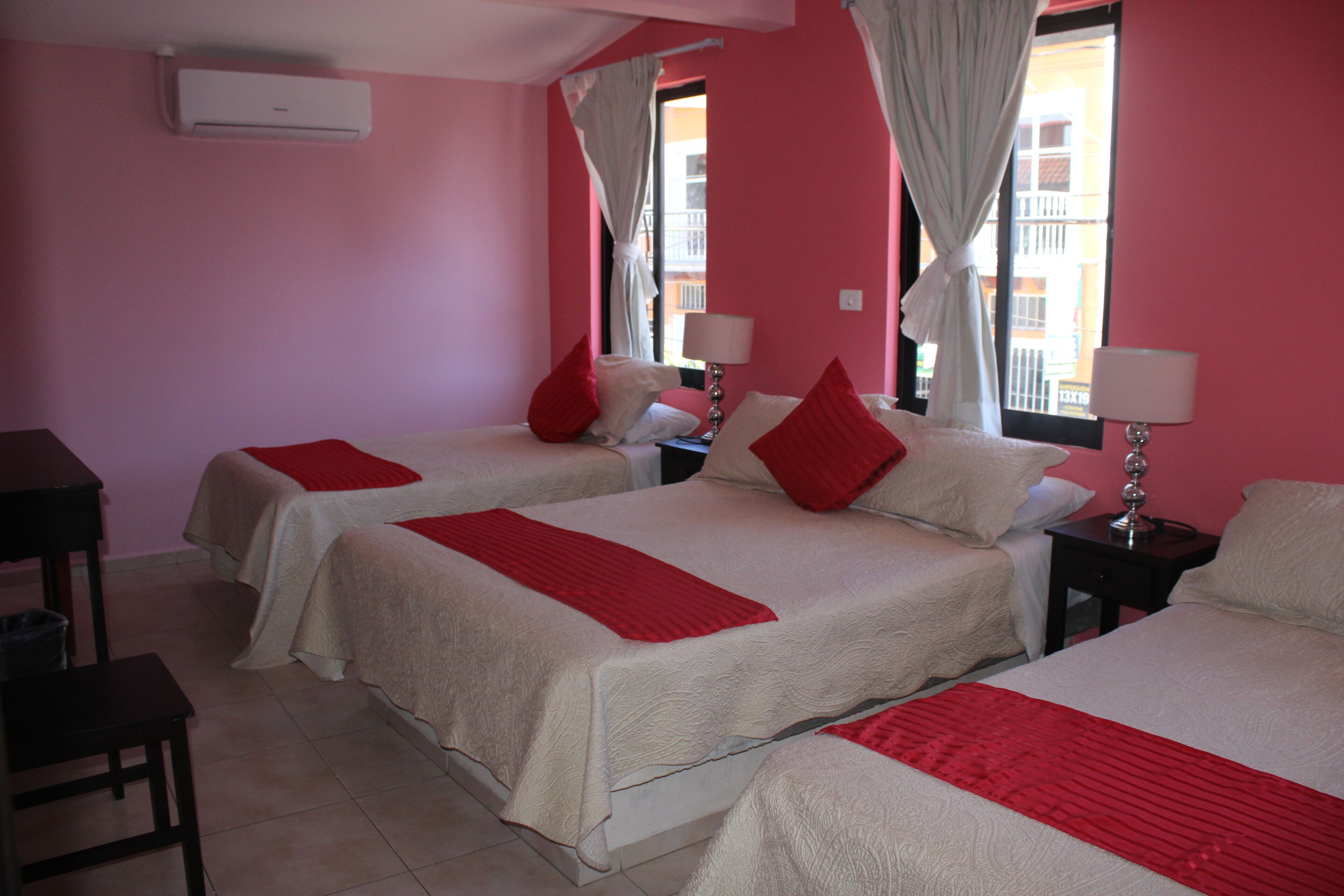 Habitación de hotel con dos camas, cada una con ropa de cama roja y blanca, un escritorio y una silla.