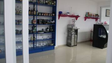 A room with blue shelving units filled with various bottles and glassware, a metal container, and a black cabinet.