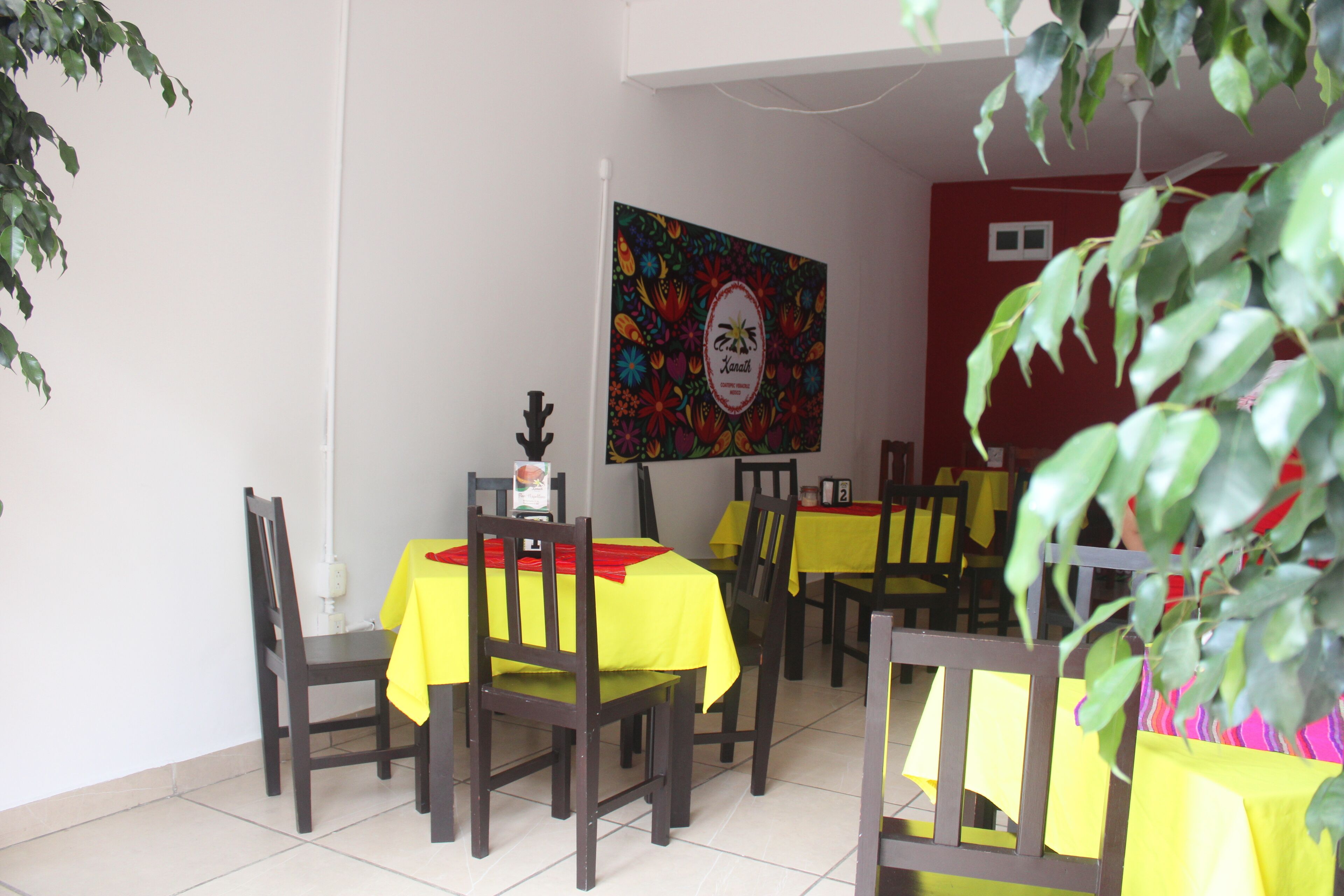 Un comedor con mesas cubiertas de manteles amarillos y sillas de madera.