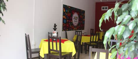 Un comedor con mesas cubiertas de manteles amarillos y sillas de madera.