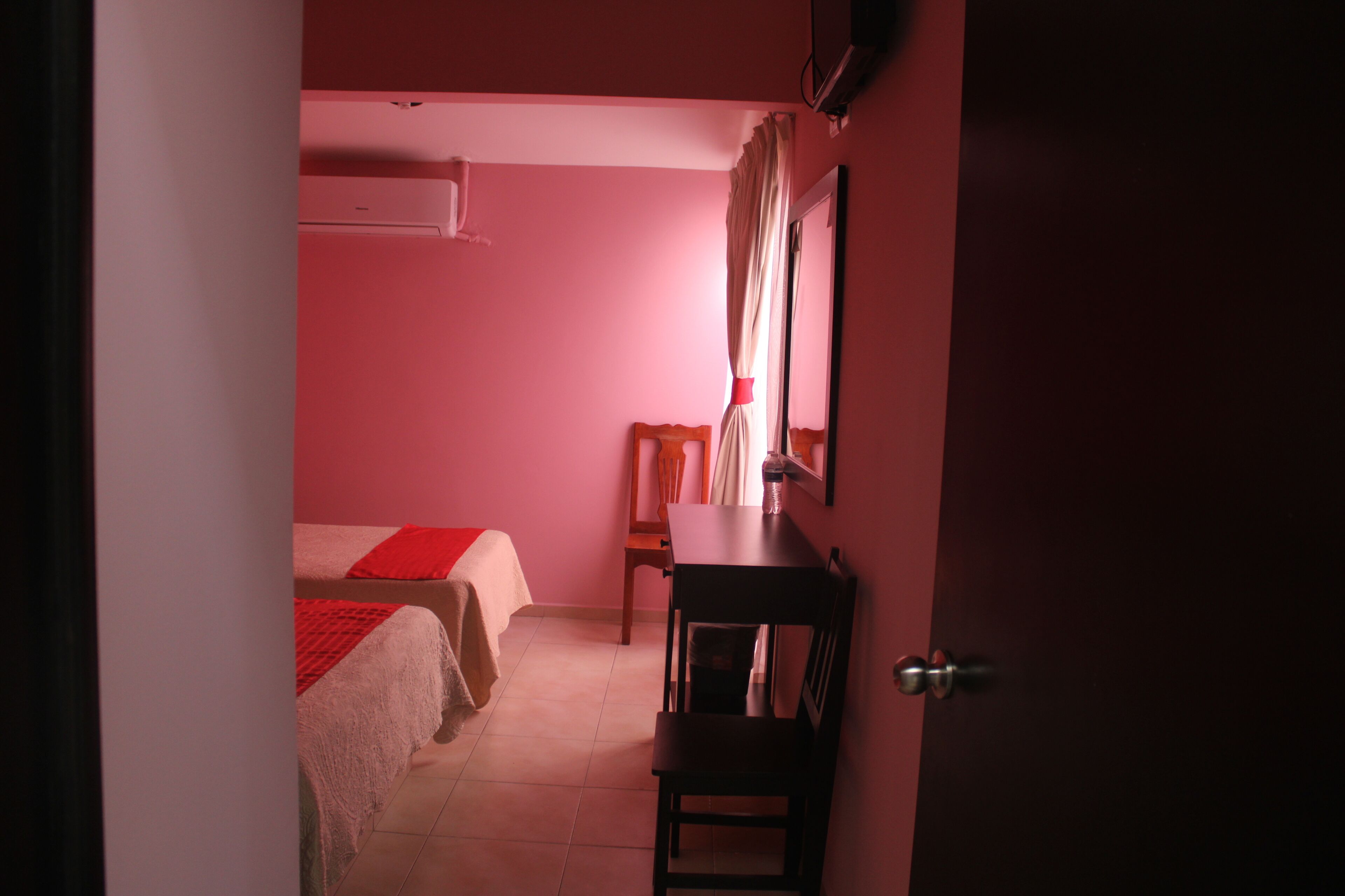 A room with two beds, a desk, a chair, and a mirror.