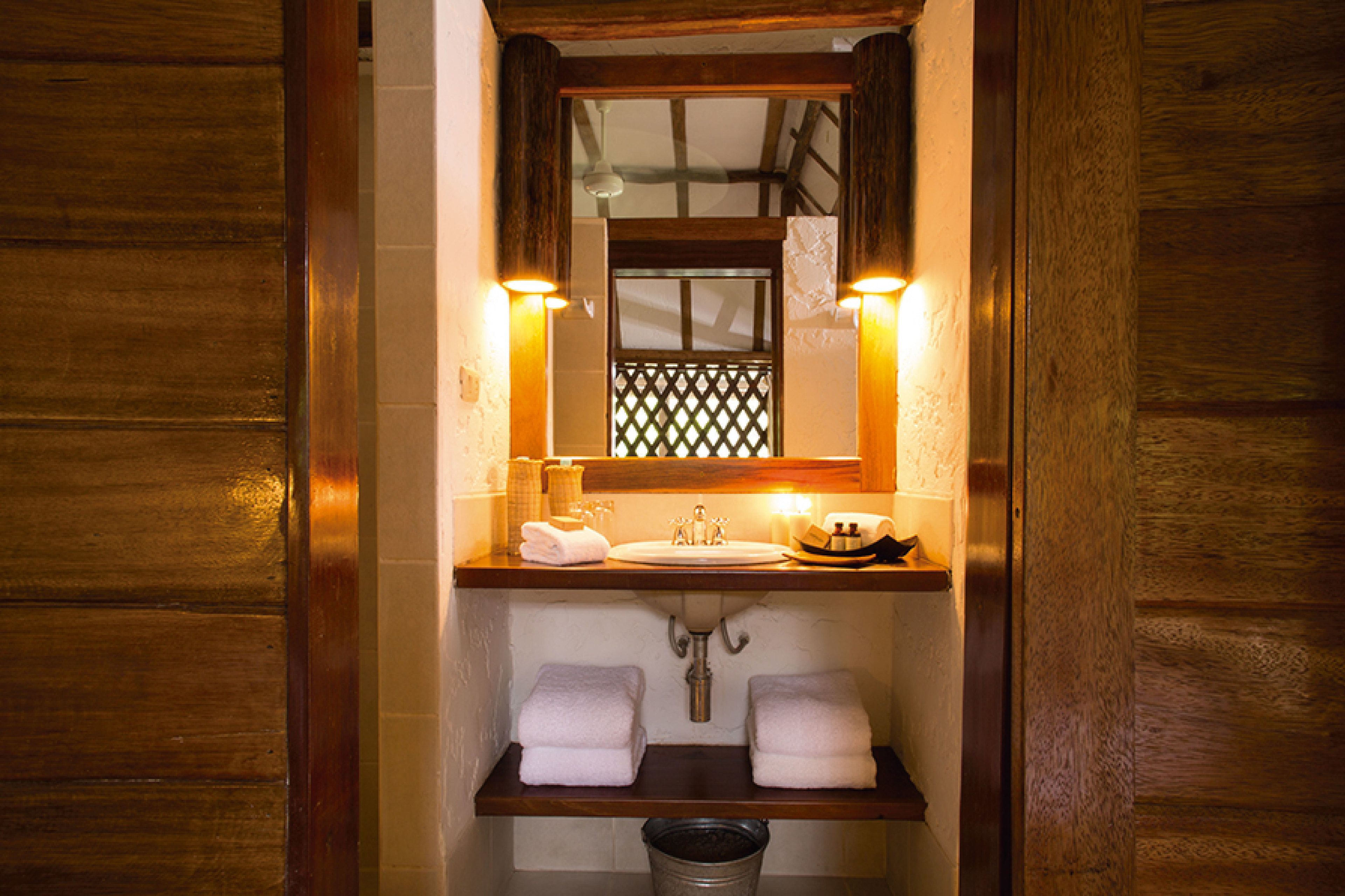 Une salle de bain avec un meuble-lavabo en bois, un évier, deux serviettes et un miroir.