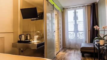 A hotel room with a bed, a desk with a chair, a shower, and a balcony with a view.