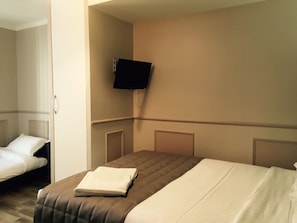 A hotel room with a single bed, a flat-screen TV mounted on the wall, and a second bed in the corner. - District Republique (Paris)