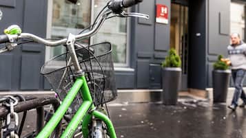 A bicycle with a green frame and a basket, parked in front of a building with a door and a sign.