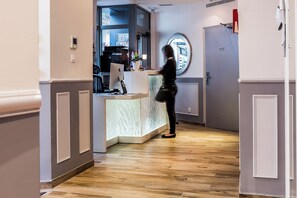 A reception area with a desk, computers, and a decorative mirror. - District Republique (Paris)