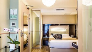 A hotel room with a bed, bedside table, lamp, and a potted plant. - District Republique (Paris)