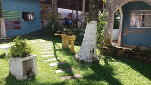 Une cour bordée d’un mur de pierre, avec un tronc d’arbre blanc et un petit jardin agrémenté de marches menant à une porte.