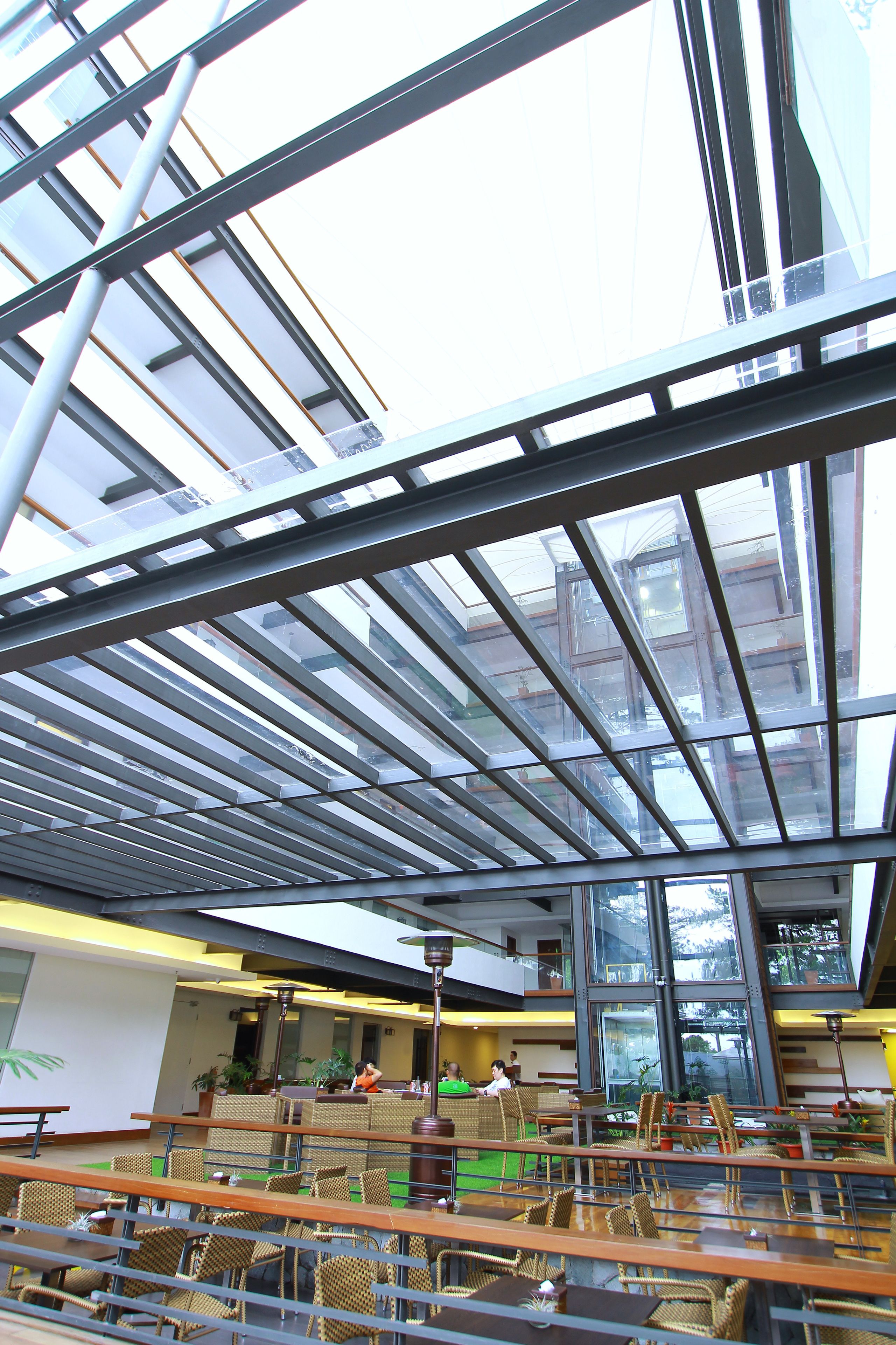 A modern indoor space with a glass ceiling, wicker furniture, and a view of the outside.