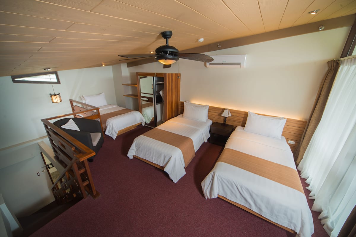 Ein Hotelzimmer mit zwei Betten, einem Deckenventilator, einem Holztisch und einem Spiegel.