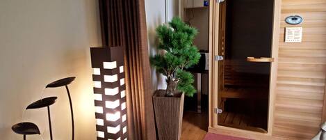 Una puerta de madera con un panel de vidrio, un árbol de hoja perenne en maceta y una lámpara de pie moderna.