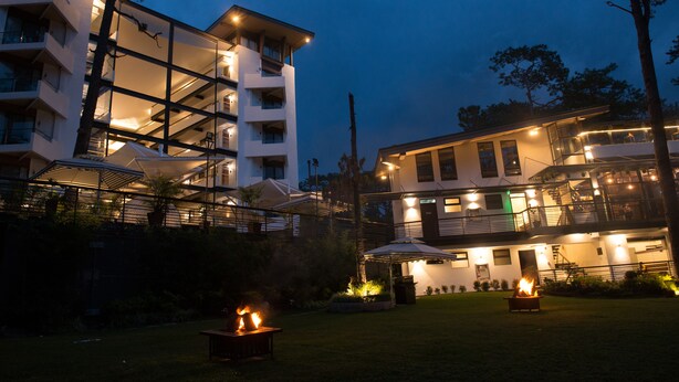 A multi-story hotel with outdoor lighting, a grassy courtyard, and a fire feature. - Grand Sierra Pines Baguio (Baguio)