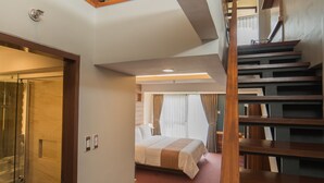 A hotel room with a wooden staircase, a glass shower, and a bed with a red carpet. - Grand Sierra Pines Baguio (Baguio)