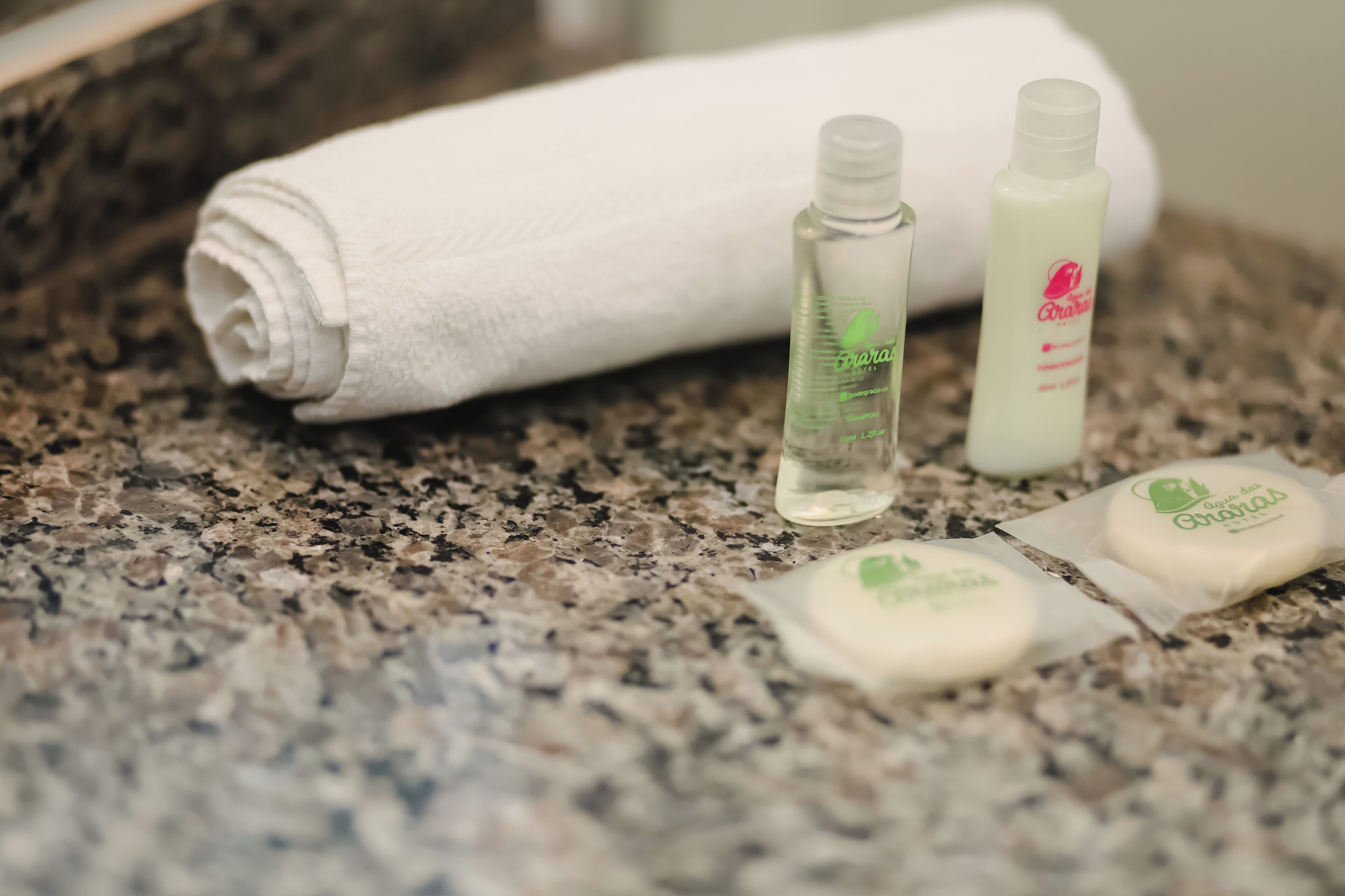 Un meuble-lavabo de salle de bain avec une serviette enroulée, un flacon de savon liquide et deux savons en pain.