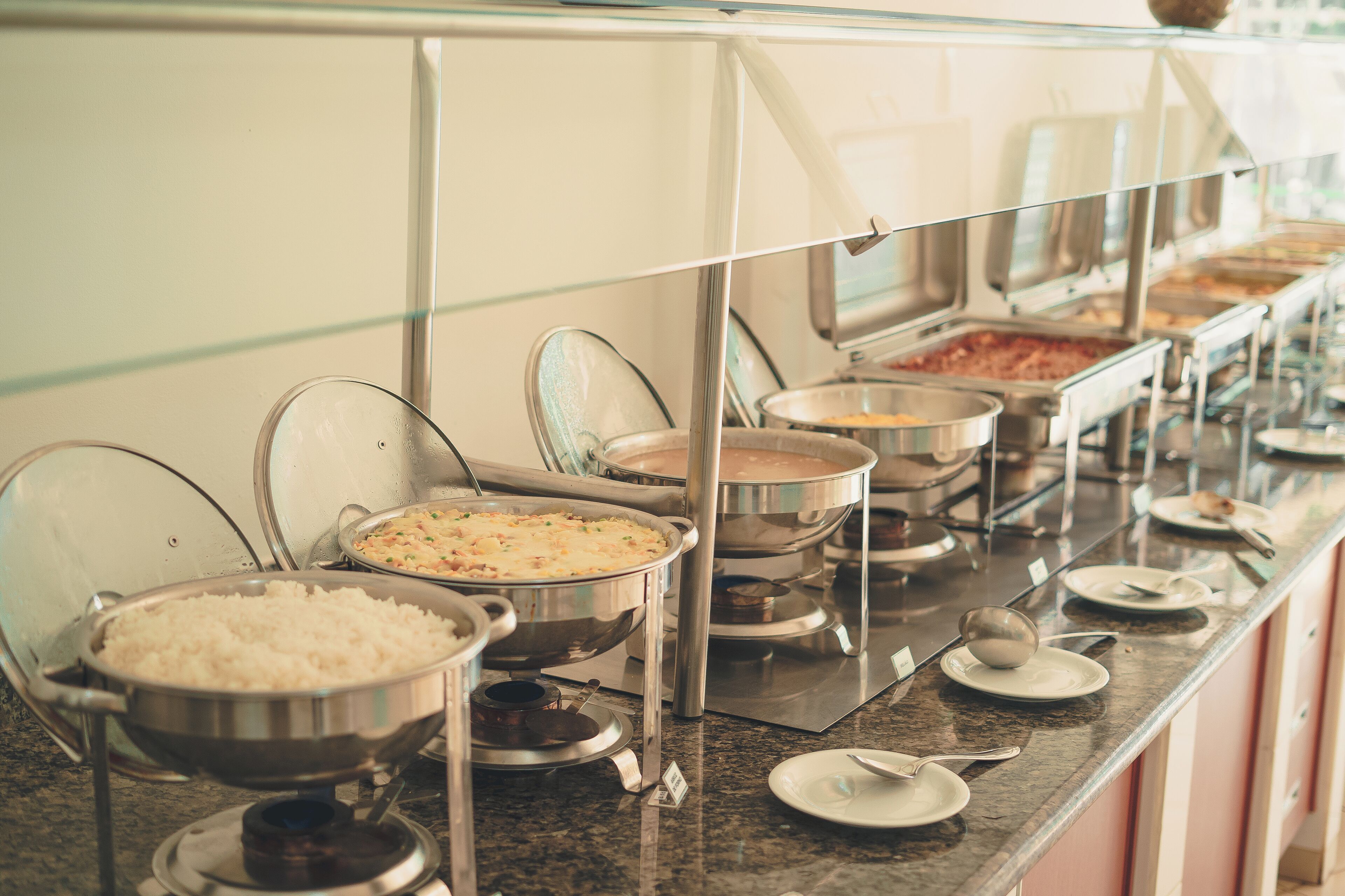 Disposição de buffet com diversos recipientes de comida e utensílios de servir.